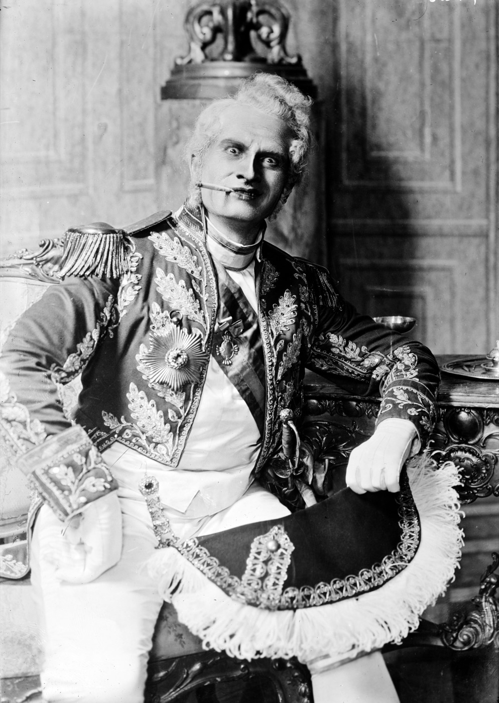 Bass Adamo Didur seated in an embroidered court uniform, in costume for Eugene Onegin