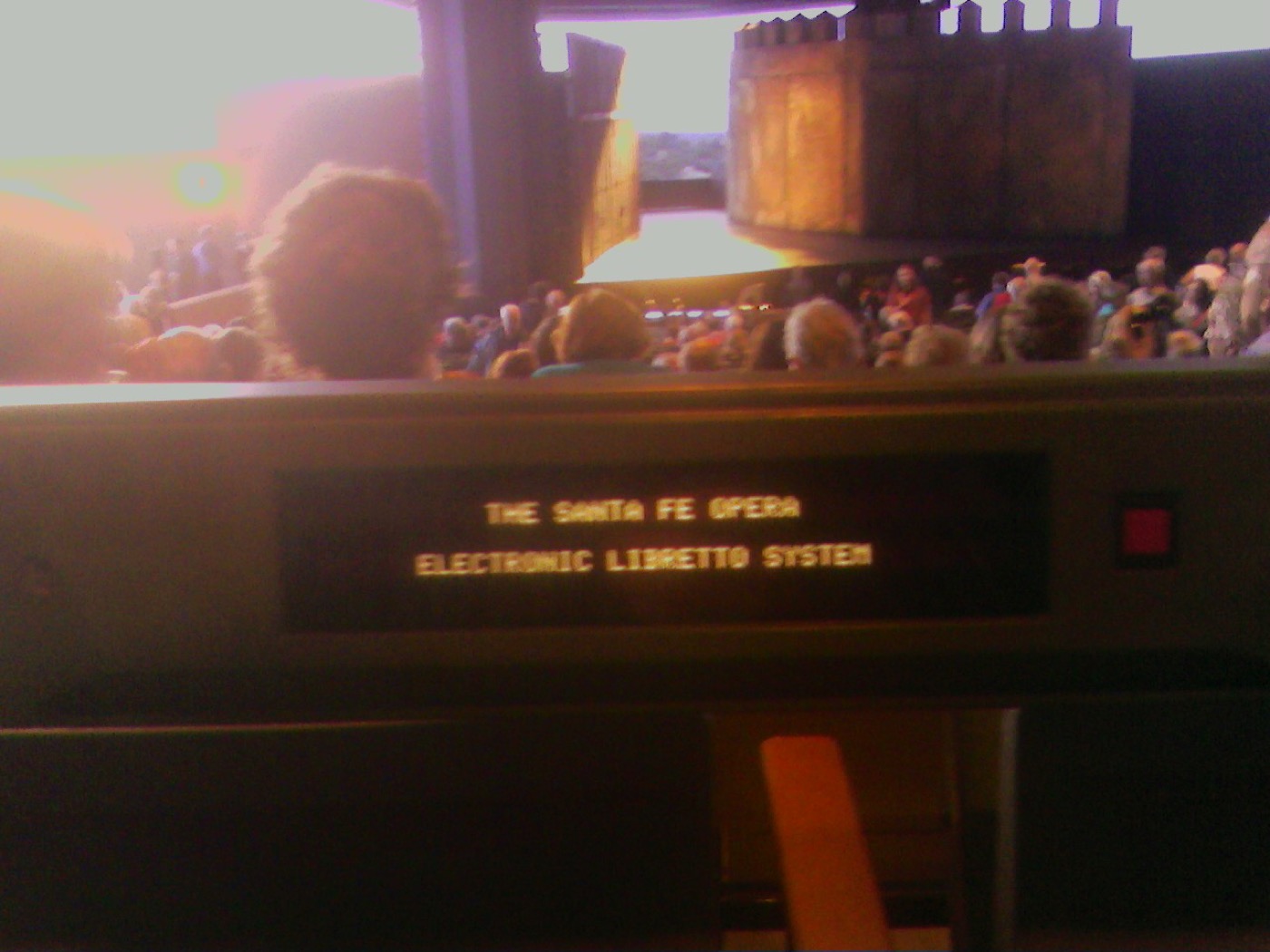 Electronic libretto display reading The Santa Fe Opera, with the audience in the background